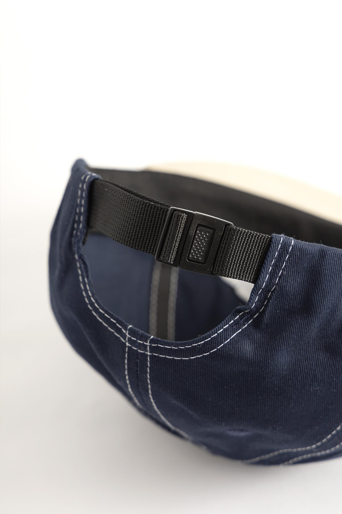 Close-up view of navy and khaki 6-panel cap showing embroidered Arch Logo and contrast stitch detailing