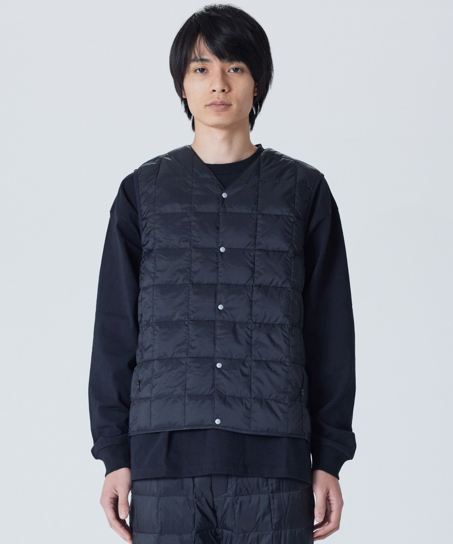 Model wearing TAION Men's V-Neck Button Down Down Vest in Black with lightweight 800 Fill Power insulation