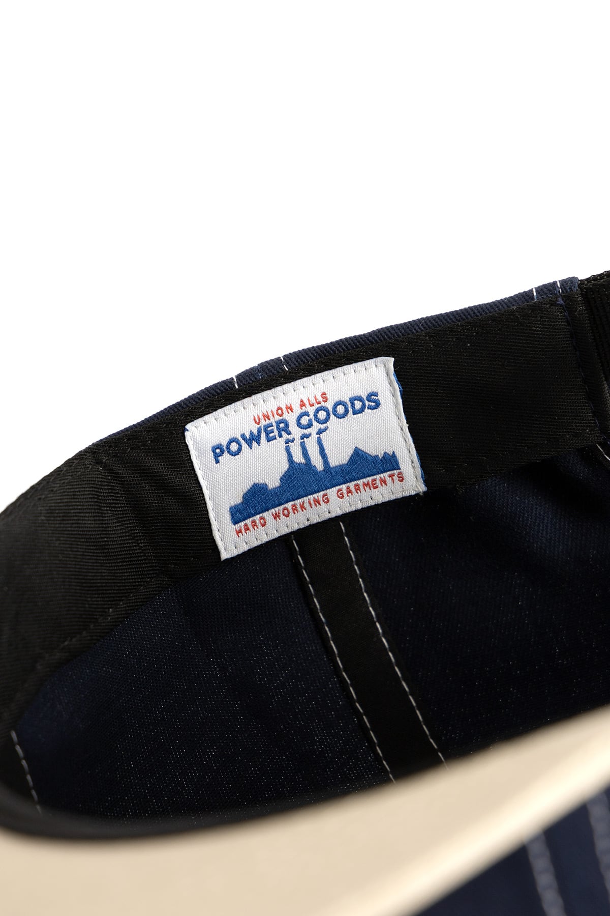 Navy cap with khaki contrast stitching and embroidered arch logo on front, studio shot on plain background
