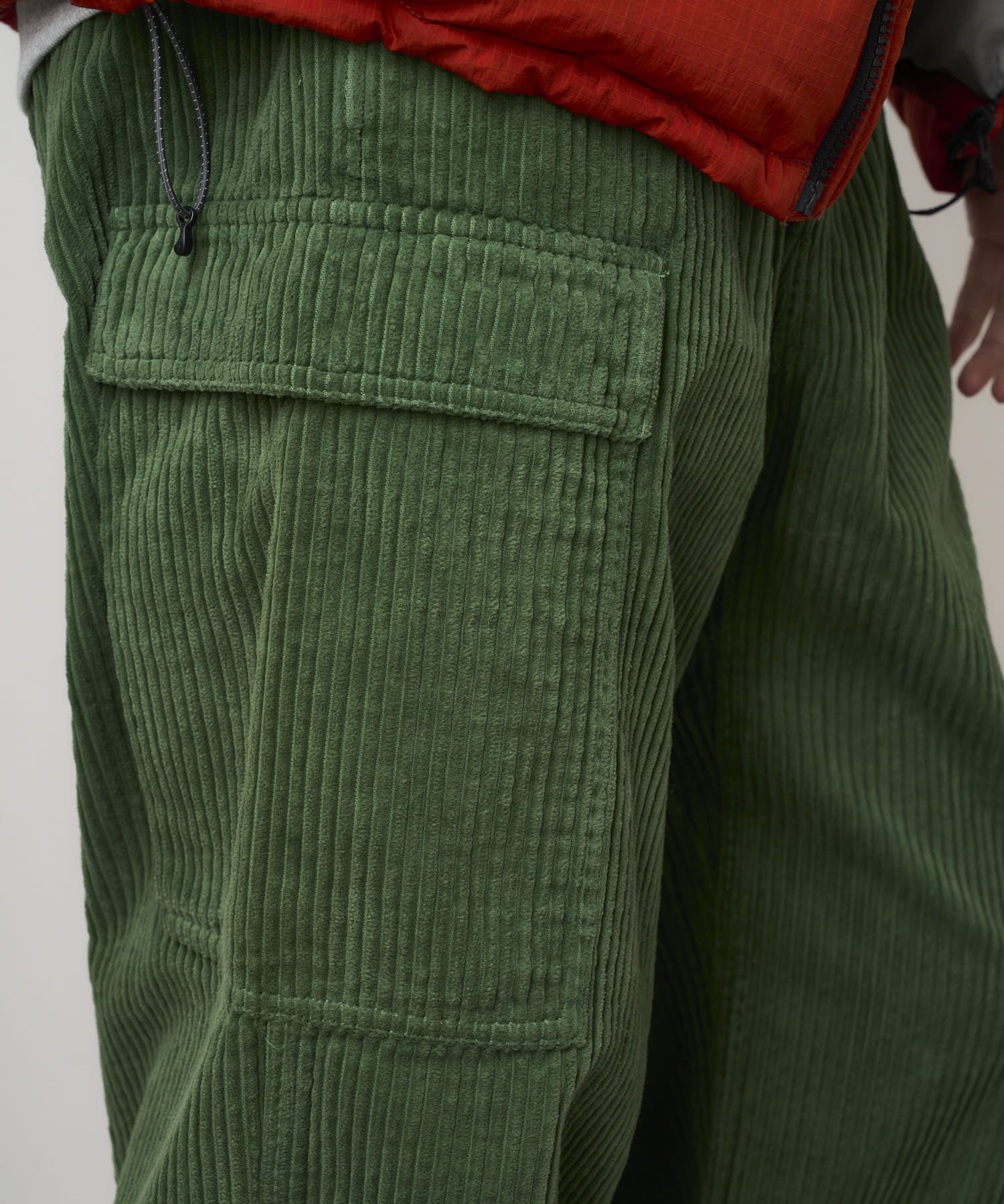 Close-up view of Pine Green corduroy cargo pants worn by model, highlighting fabric texture, relaxed silhouette and utility design