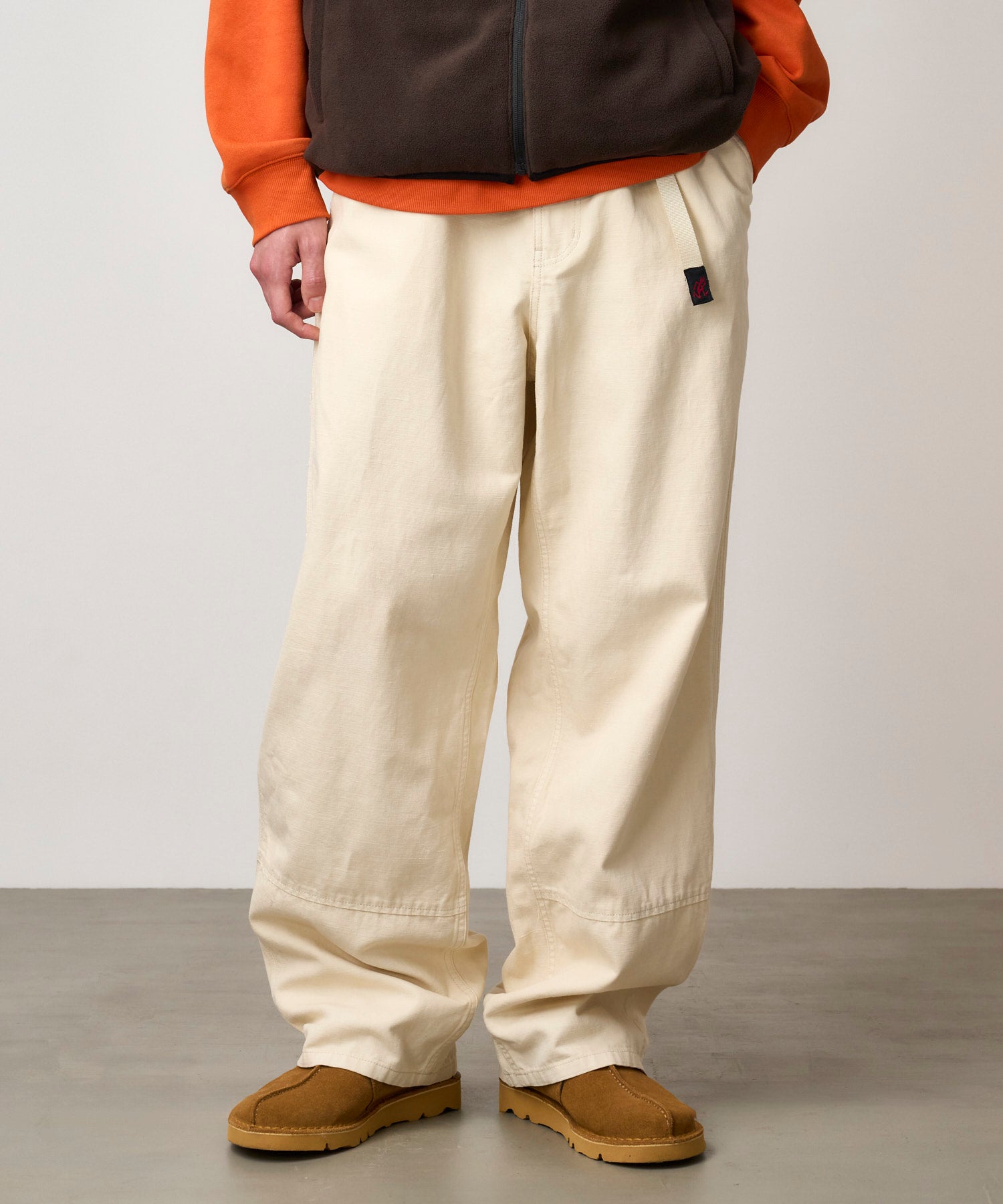 Model wearing bone canvas work pants shown from side angle, featuring relaxed fit, durable hemp-cotton fabric and utility pockets