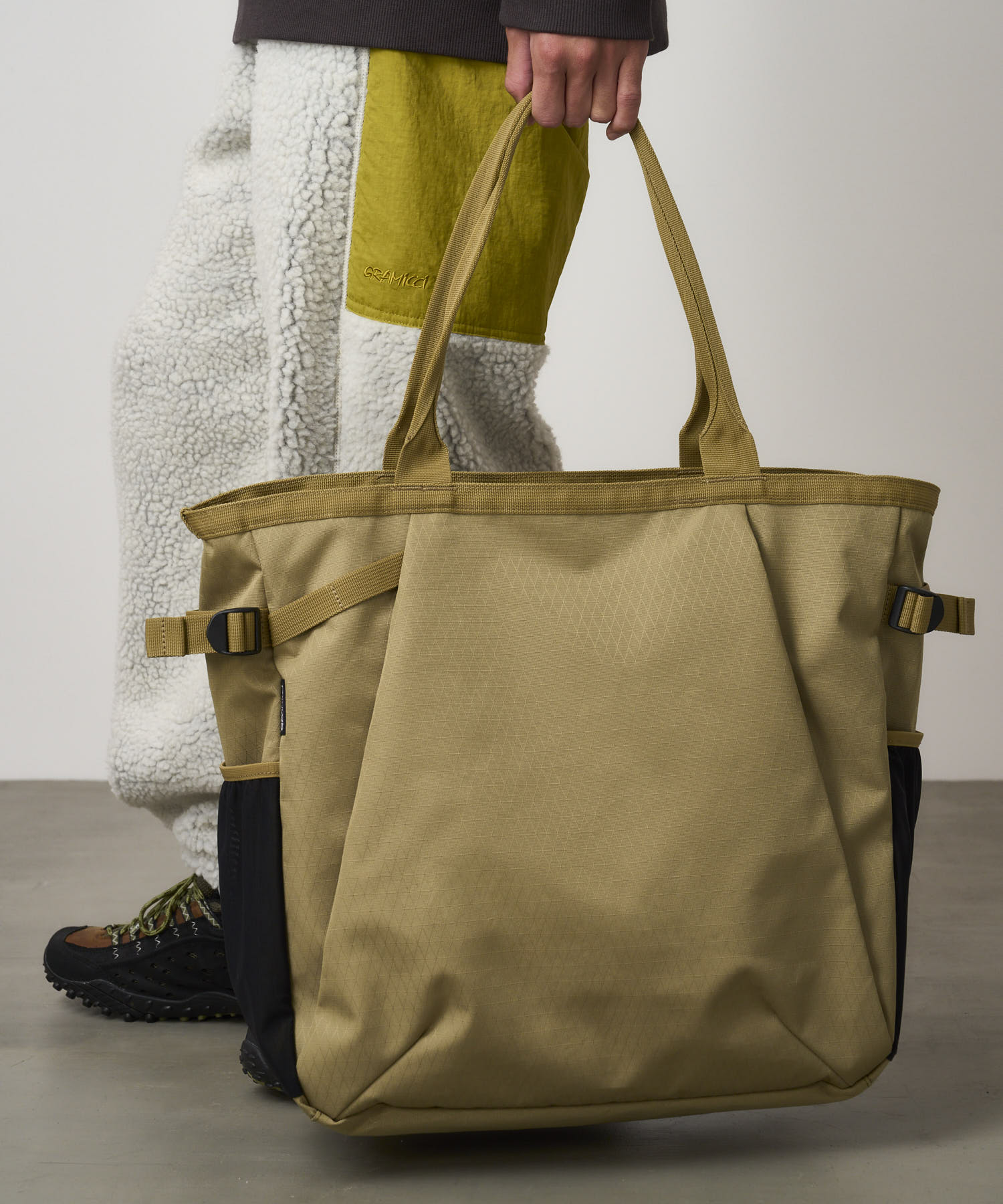 Model carrying Bronze Olive Climbing Tote bag made from recycled CORDURA nylon, designed for travel, work and everyday carry