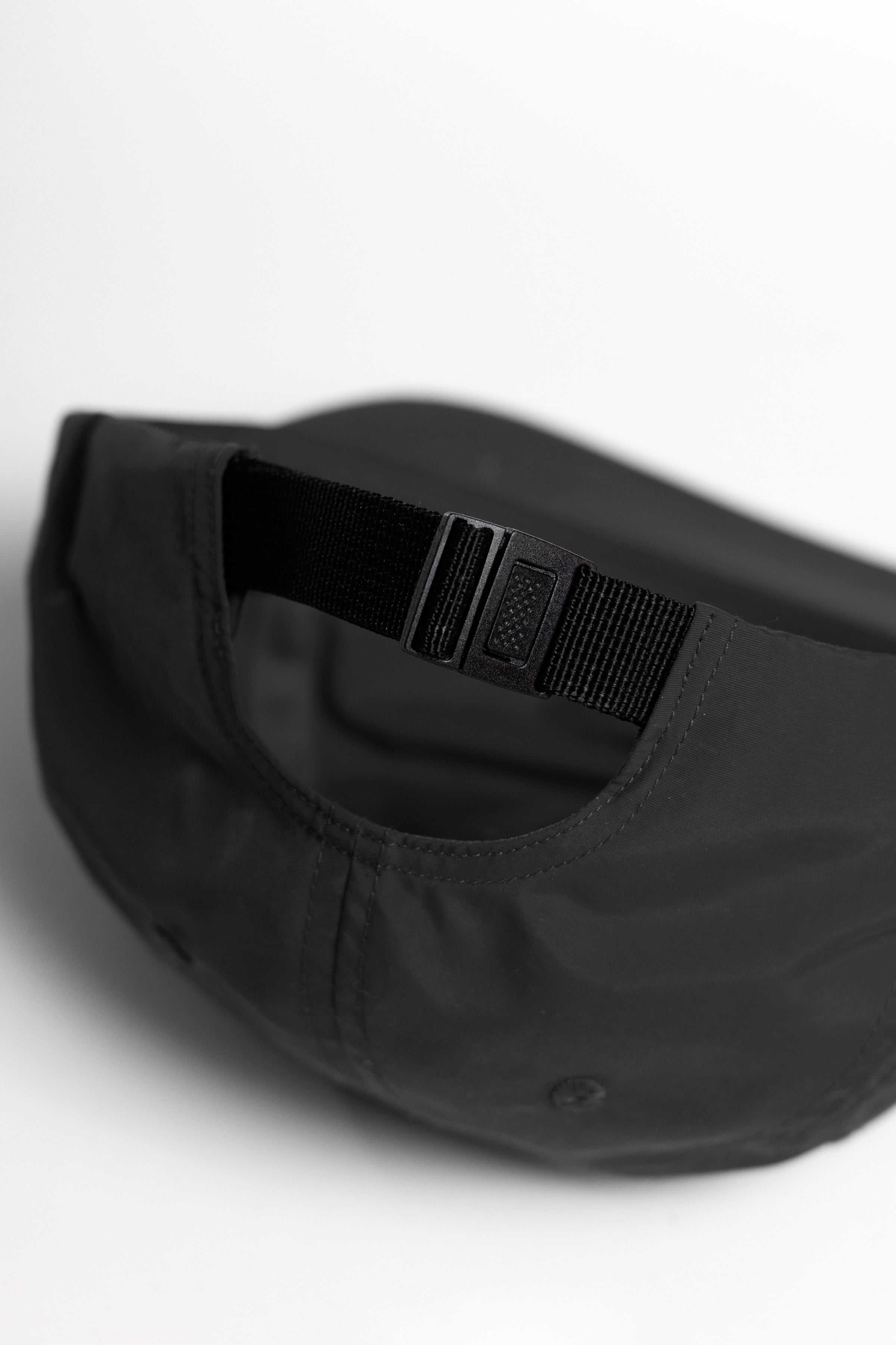 Model wearing black Chefs Kiss Cap shown from back, featuring unstructured nylon construction, curved brim and adjustable strap for secure fit