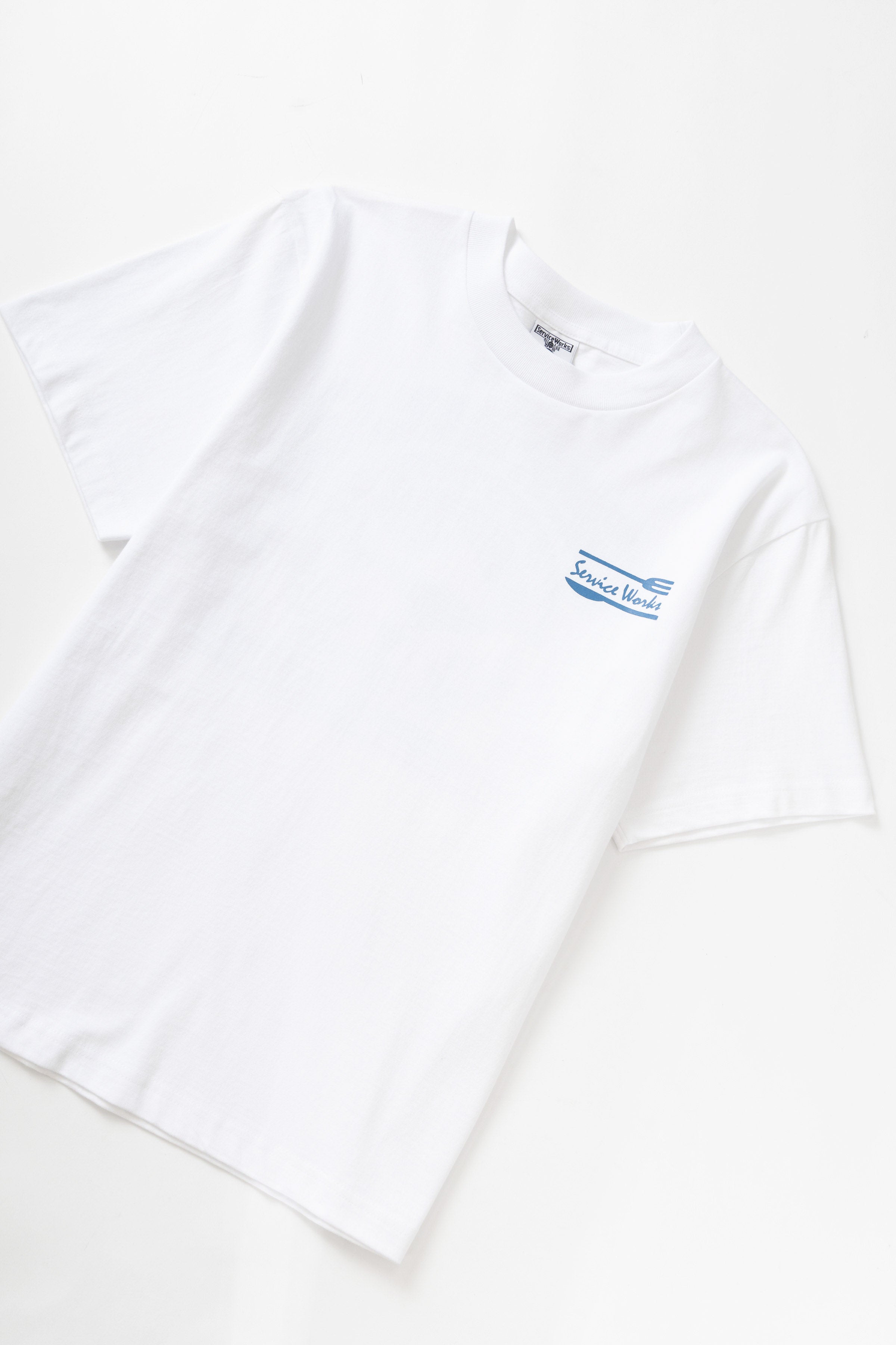 Close-up of white Milos Tee worn by model, featuring premium organic cotton fabric, standard fit and clean streetwear aesthetic