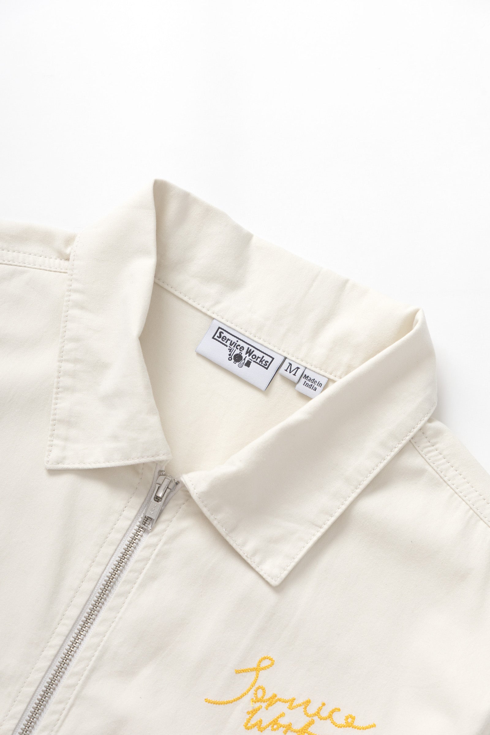 Close-up detail of off white twill work jacket showing fabric texture and craftsmanship