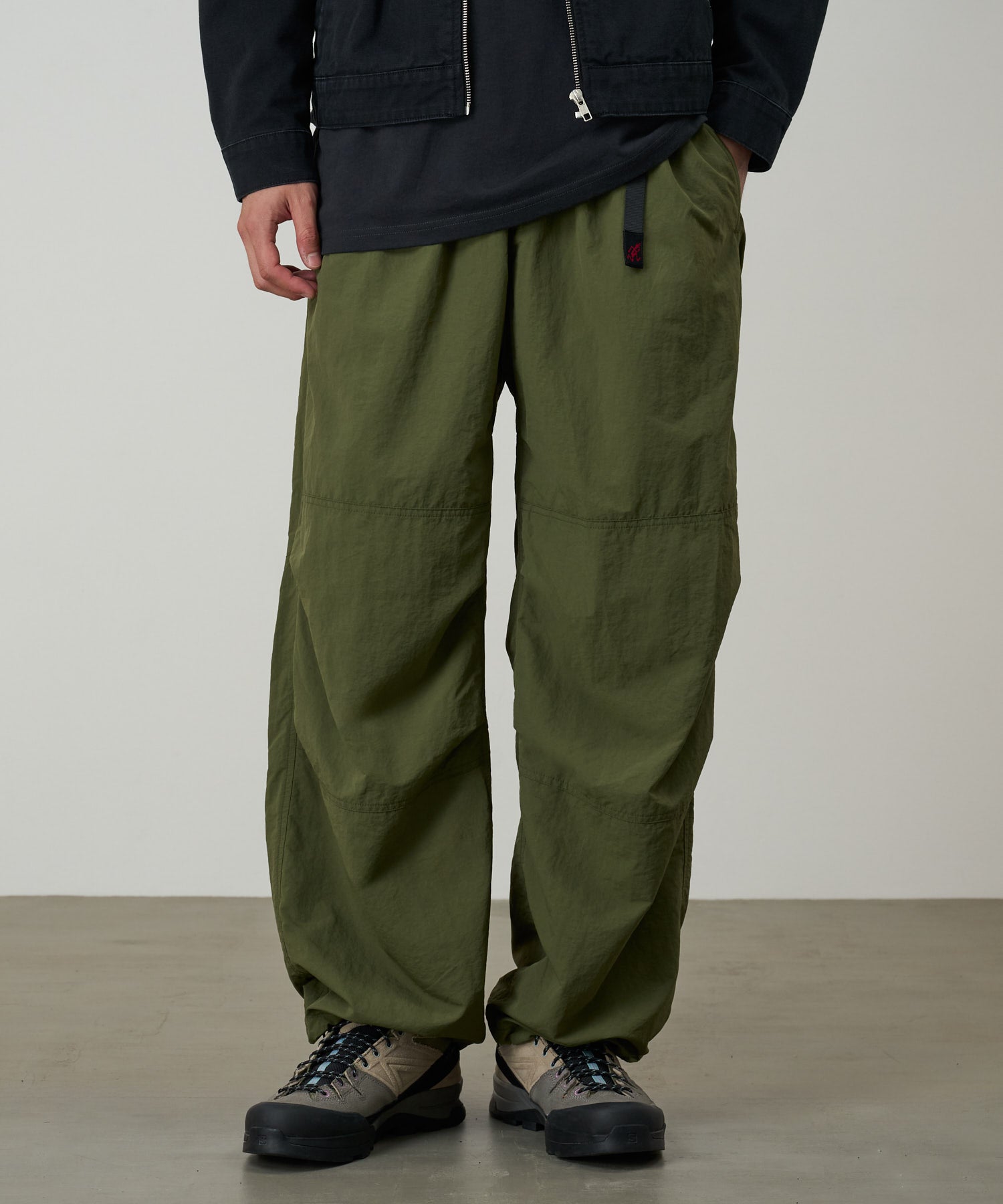 Model wearing olive nylon paneled trek pants with wide-leg relaxed fit, lightweight durable utility trousers for everyday wear
