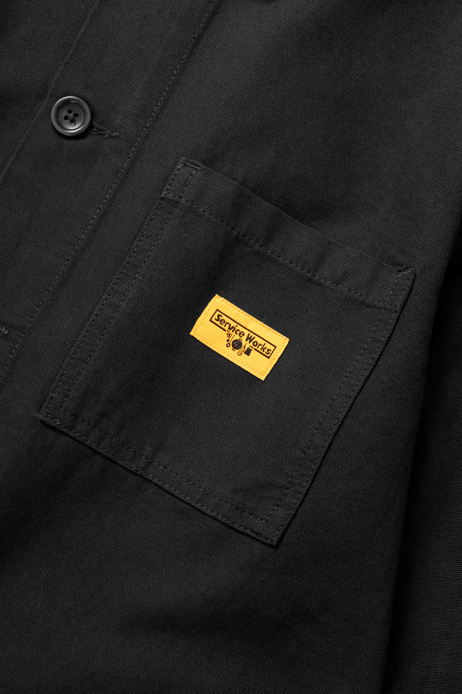 Close-up of the Service Works Canvas Chore Shirt in Black showing chest pocket design and reinforced stitching details.