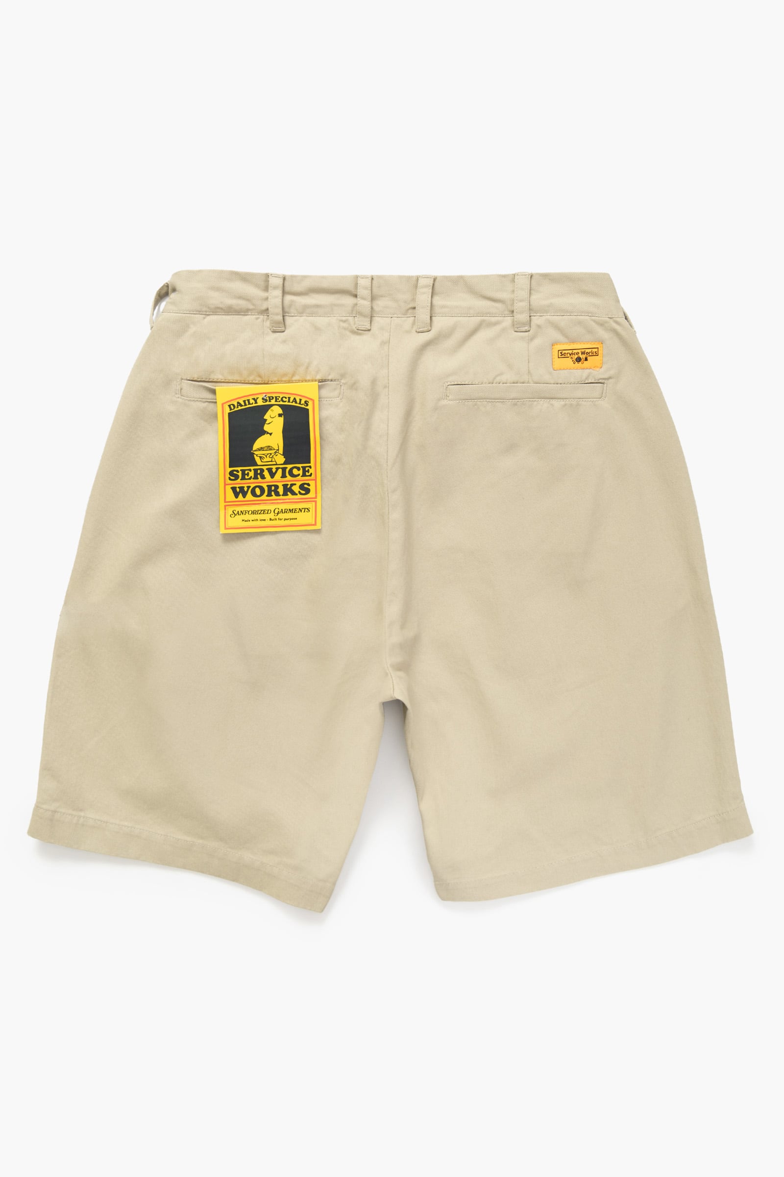 Khaki Service Works work shorts with yellow brand label close-up