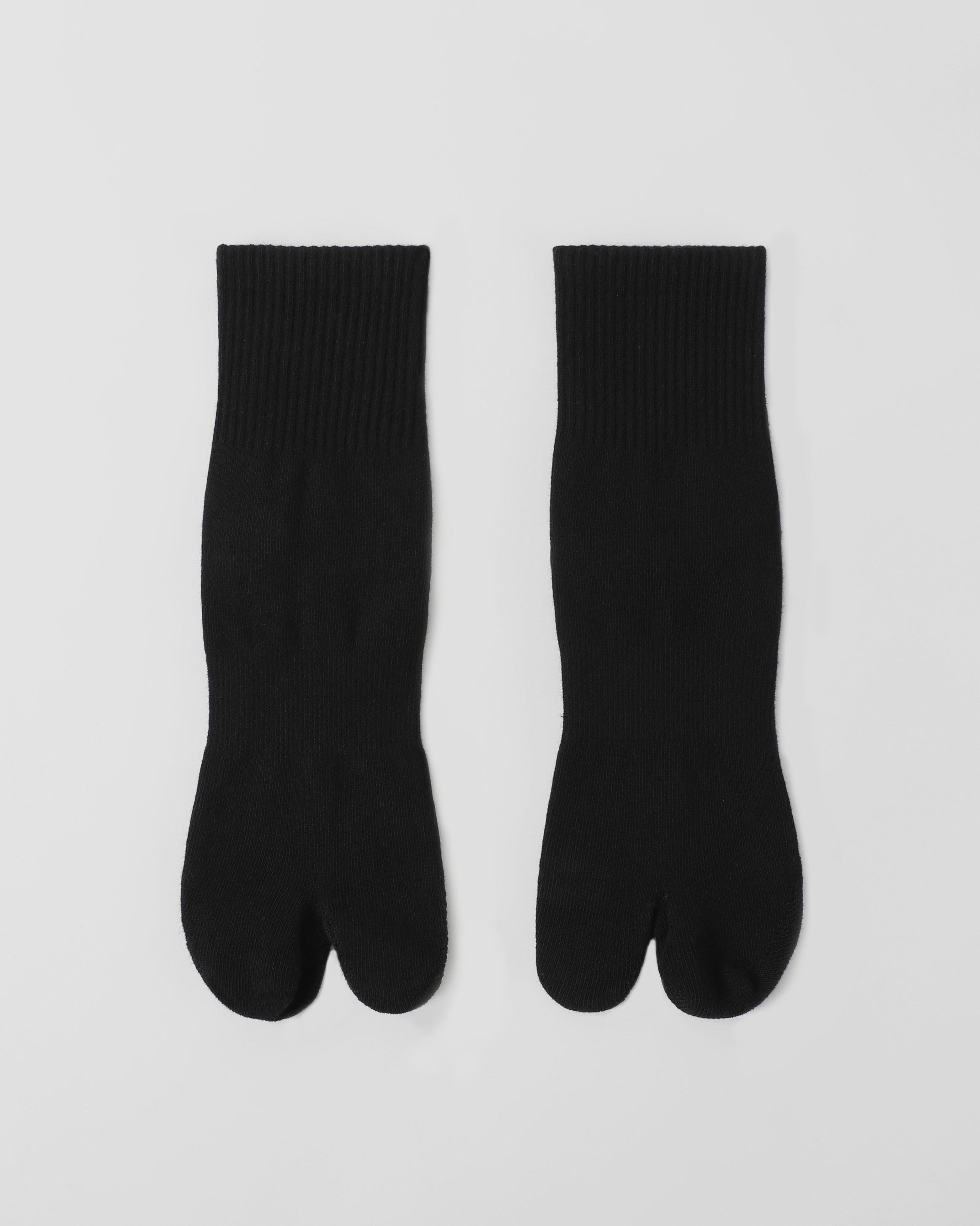 Flat lay of black tabi split-toe socks made from cotton blend fabric with breathable stretch and comfortable everyday fit.
