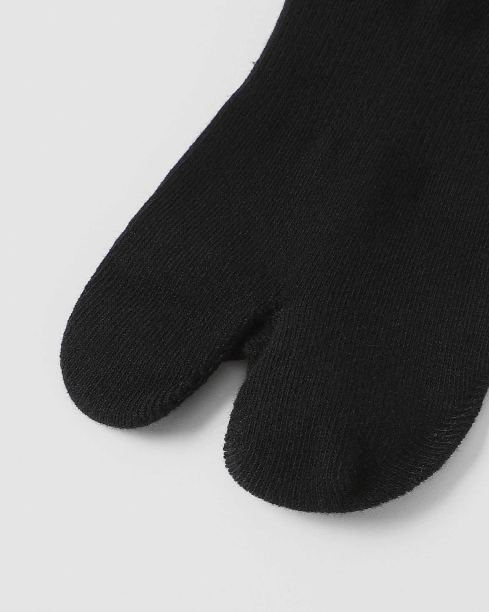 Model wearing black tabi split-toe socks made from cotton blend fabric with stretch and breathable everyday comfort fit.