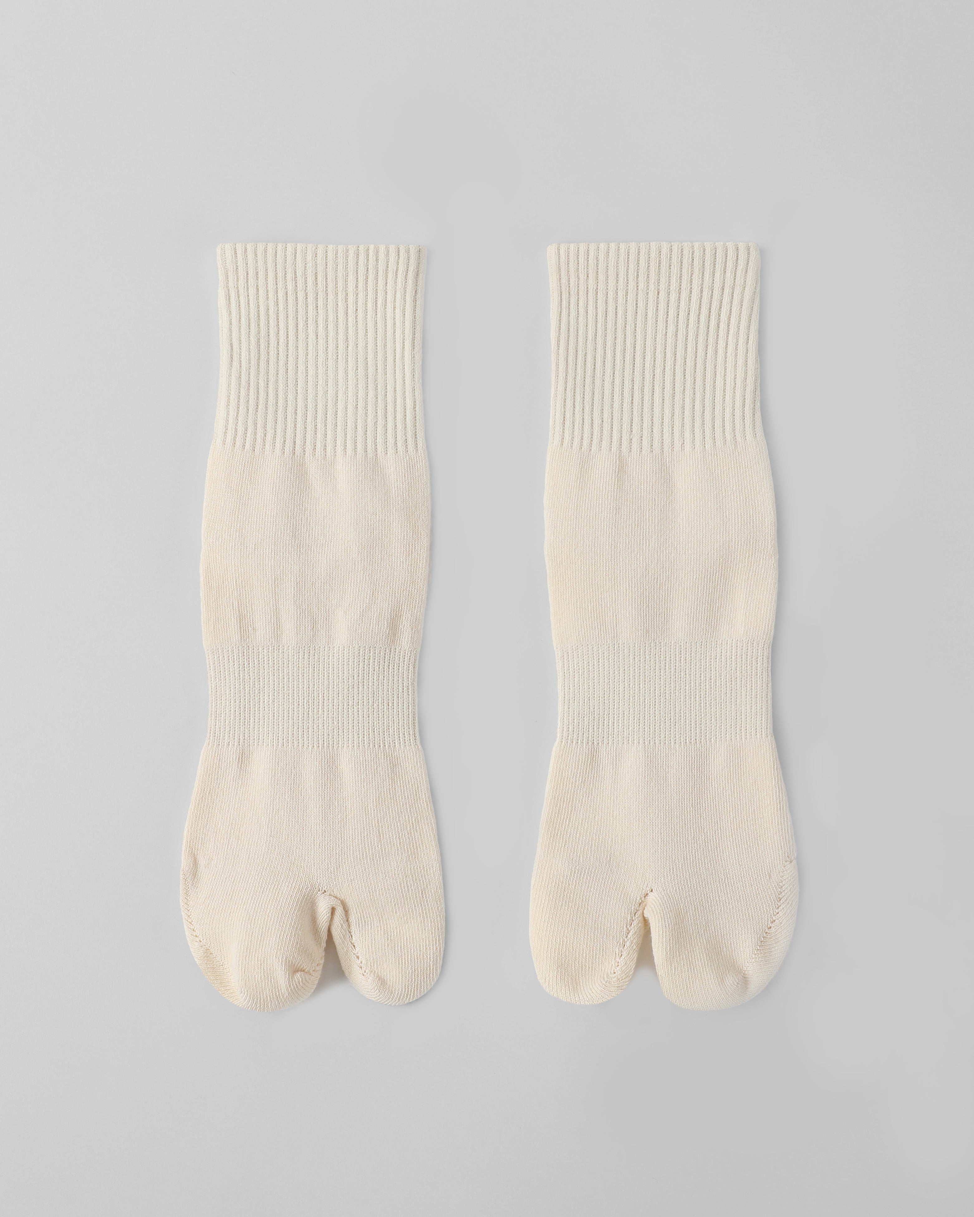 Flat lay of off white tabi split-toe socks made from cotton blend fabric with stretch and breathable everyday comfort.
