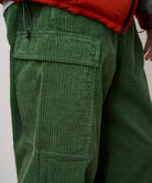 Close-up view of Pine Green corduroy cargo pants worn by model, highlighting fabric texture, relaxed silhouette and utility design