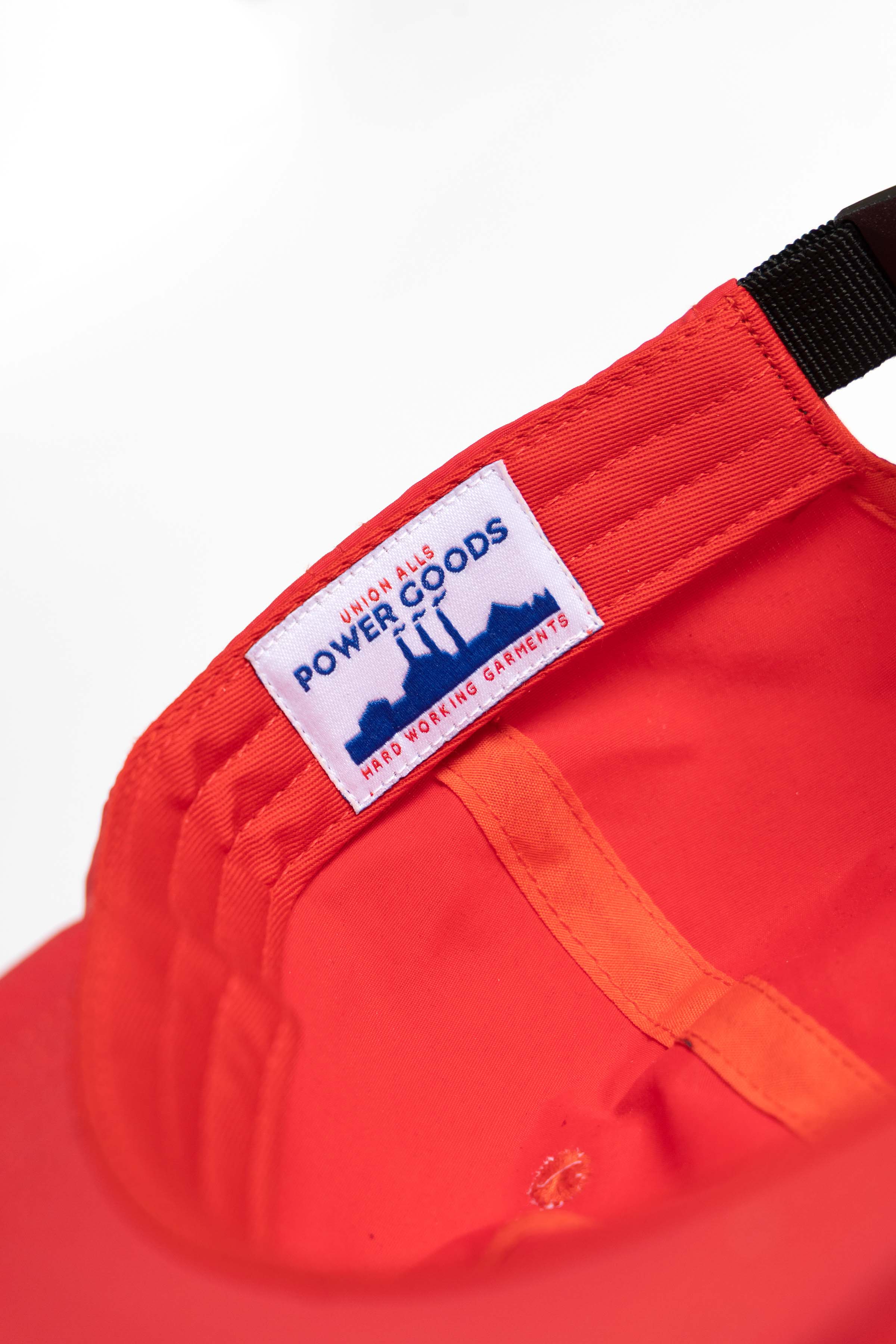 Detail view of red Chefs Kiss Cap highlighting curved peak brim, nylon fabric texture and unstructured low profile design