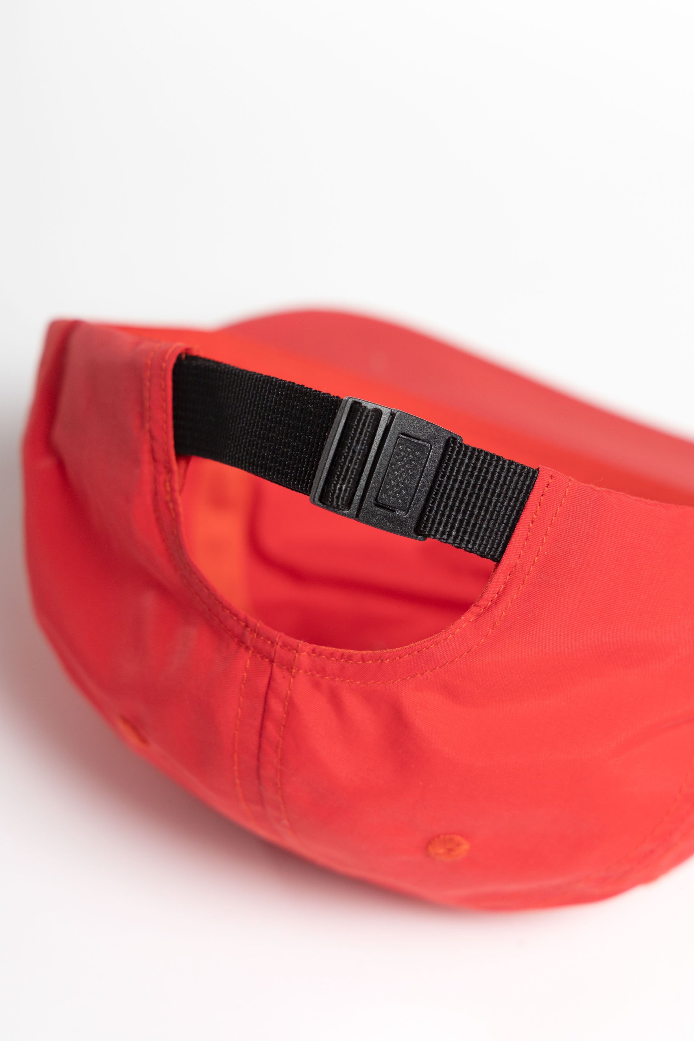 Model wearing red Chefs Kiss Cap shown from back, featuring nylon construction, curved brim and adjustable webbed strap for secure fit
