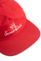 Front view of model wearing red Chefs Kiss Cap with unstructured nylon design, curved peak brim and relaxed streetwear fit