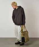 Bronze Olive Climbing Tote bag carried by model, featuring durable recycled CORDURA nylon, heavy-duty straps and versatile everyday storage