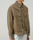Model wearing beige corduroy trucker jacket shown from side angle, featuring workwear pockets and durable cotton corduroy construction