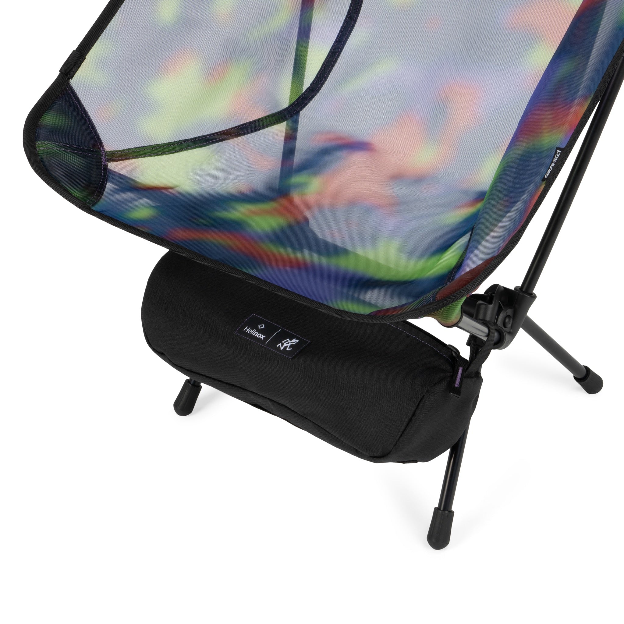 Angled detail view of Gramicci & Helinox Chair One in camo showing lightweight frame and tie-dyed mesh fabric construction