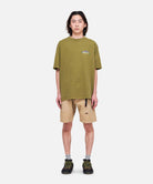 Model wearing Gramicci Mountaineering Tee Pistachio Pigment in eco cotton with regular fit and outdoor-inspired graphic for everyday wear.