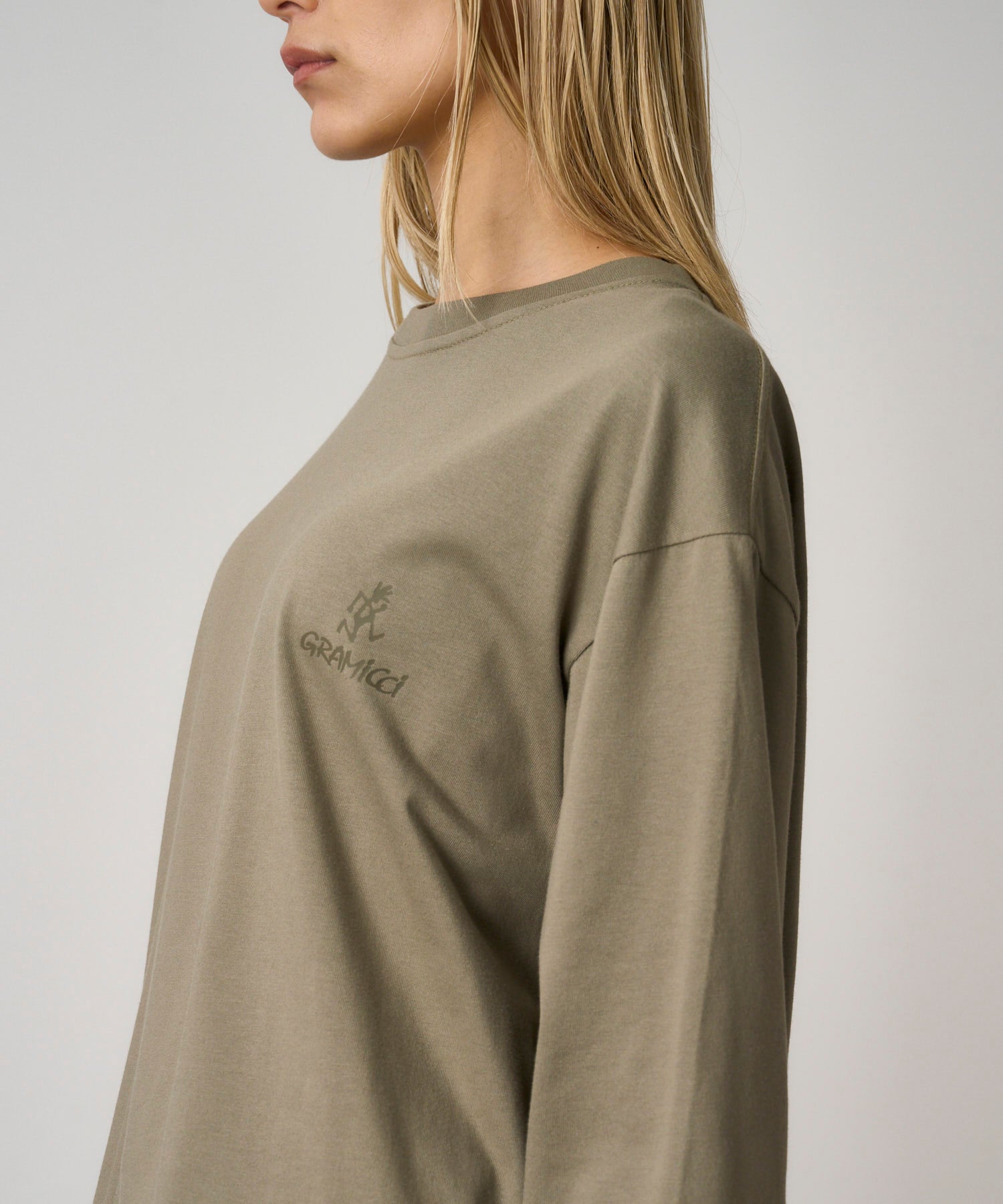 Model wearing khaki long sleeve t-shirt with regular fit and chest logo, styled for casual everyday comfort and streetwear