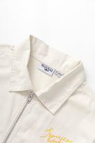 Close-up detail of off white twill work jacket showing fabric texture and craftsmanship