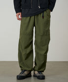 Model wearing olive nylon paneled trek pants with wide-leg relaxed fit, lightweight durable utility trousers for everyday wear