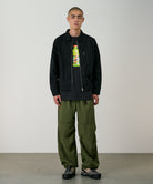 Side view of model wearing olive nylon paneled trek pants with wide-leg relaxed fit and lightweight durable fabric for everyday wear