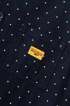 Detail view of navy polka dot chore shirt highlighting organic cotton drill fabric, button-up front and durable workwear stitching