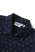 Model wearing navy polka dot chore shirt shown from back, featuring organic cotton fabric, relaxed silhouette and classic workwear design