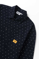 Model wearing navy polka dot chore shirt shown from side angle, featuring organic cotton fabric, relaxed silhouette and utility workwear style