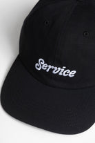 Model wearing Ripstop Service Cap in black made from durable cotton ripstop fabric with structured fit and curved brim for everyday wear