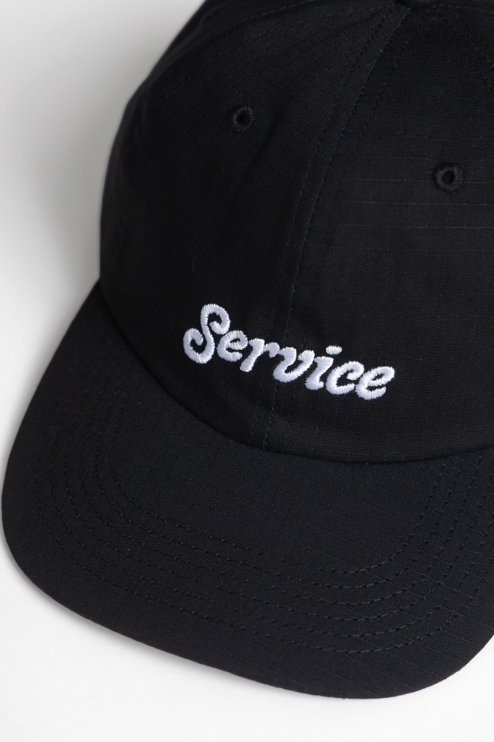 Model wearing Ripstop Service Cap in black made from durable cotton ripstop fabric with structured fit and curved brim for everyday wear