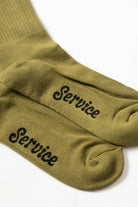 Olive Salt + Pepper crew socks by Service Works with signature graphic, side view on white background