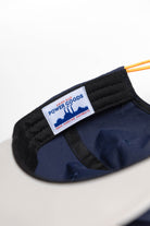 Back view of model wearing Script Surf Cap in navy and off-white with 100% cotton construction and elastic adjuster