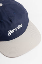 Model wearing Script Surf Cap in navy and off-white made from 100% cotton with low-profile fit, curved brim and elastic adjuster