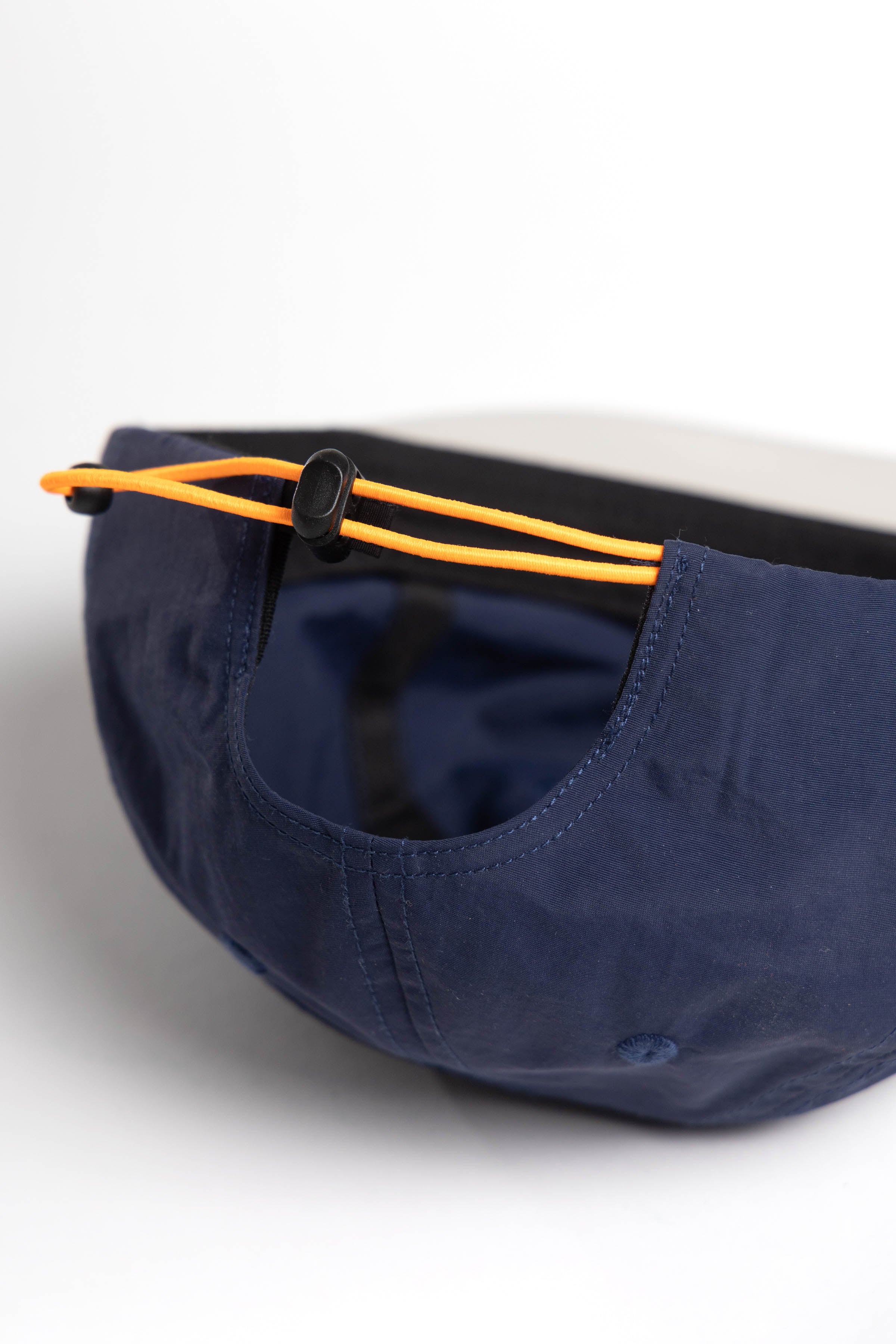 Side view of model wearing Script Surf Cap in navy and off-white with 100% cotton construction and low-profile fit