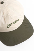 Front view of model wearing off-white and olive Script Surf Cap featuring cotton construction, relaxed surf style and curved brim design