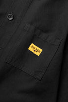 Close-up of the Service Works Canvas Chore Shirt in Black showing chest pocket design and reinforced stitching details.