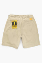 Khaki Service Works work shorts with yellow brand label close-up