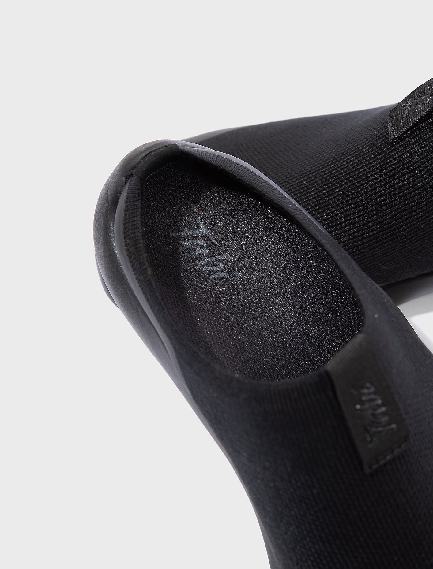Close-up detail of Tabi Mules Black showing brand logo, split-toe knit upper and premium lightweight construction.