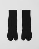 Flat lay of black tabi split-toe socks made from cotton blend fabric with breathable stretch and comfortable everyday fit.
