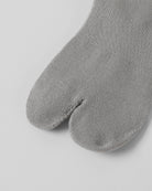Close-up of grey tabi socks showing split toe design in soft cotton fabric