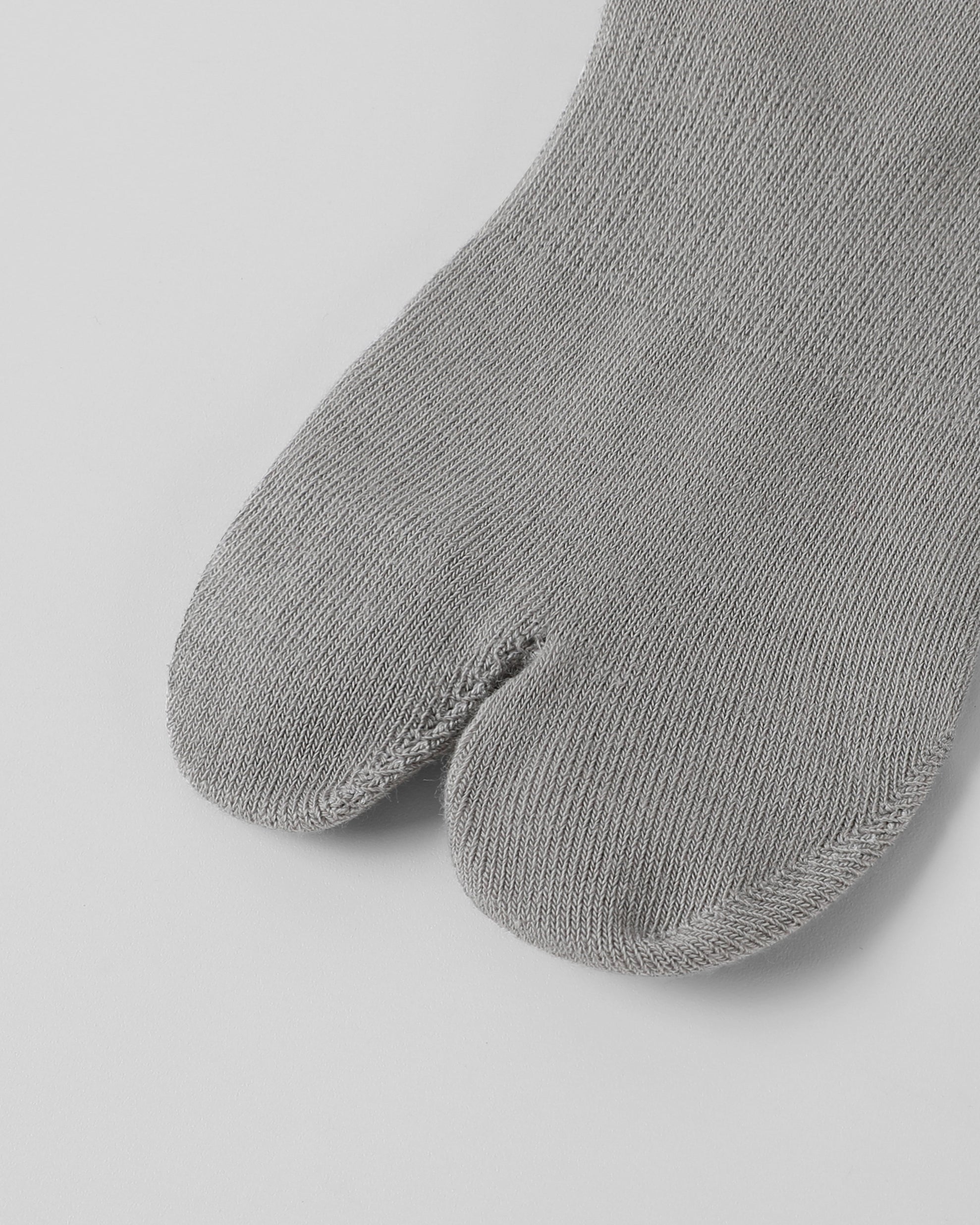 Close-up of grey tabi socks showing split toe design in soft cotton fabric