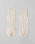 Flat lay of off white tabi split-toe socks made from cotton blend fabric with stretch and breathable everyday comfort.